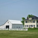 a large white house sitting on top of a lush green field