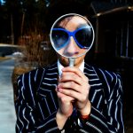 person using magnifying glass enlarging the appearance of his nose and sunglasses